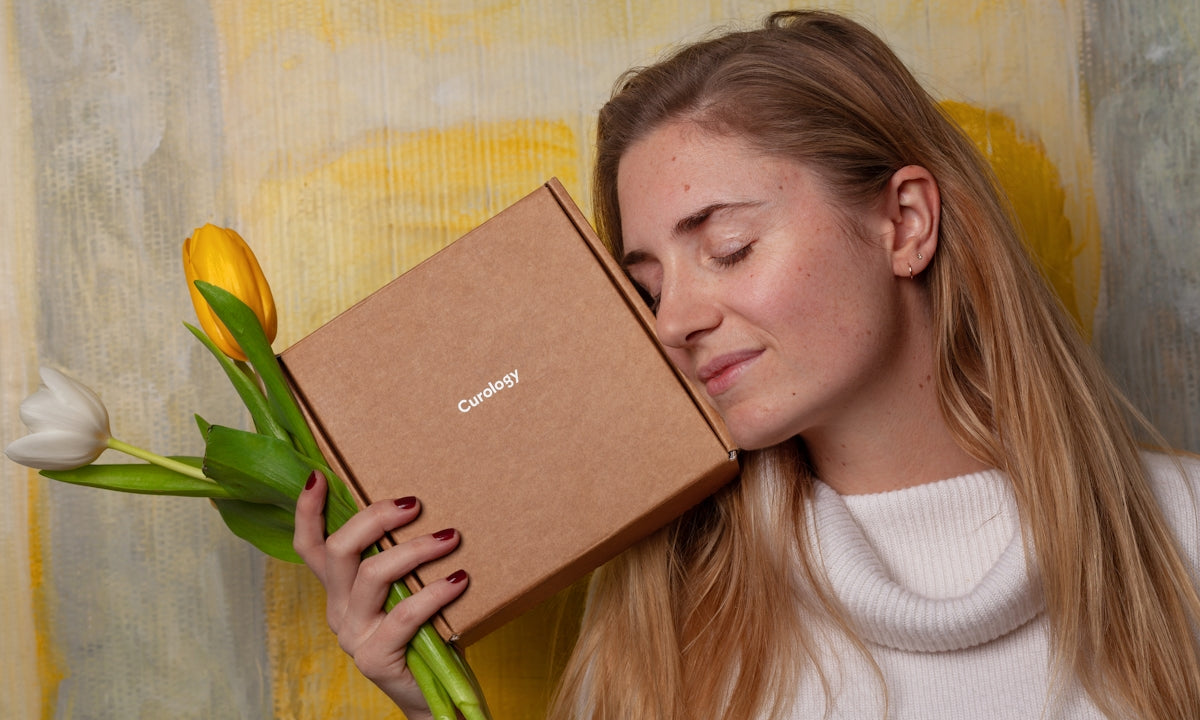 woman in white sweater holding brown box and tulip flowers