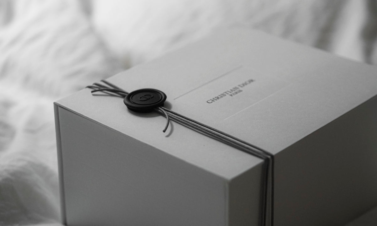 A white gift box tied with ribbon and wax seal.