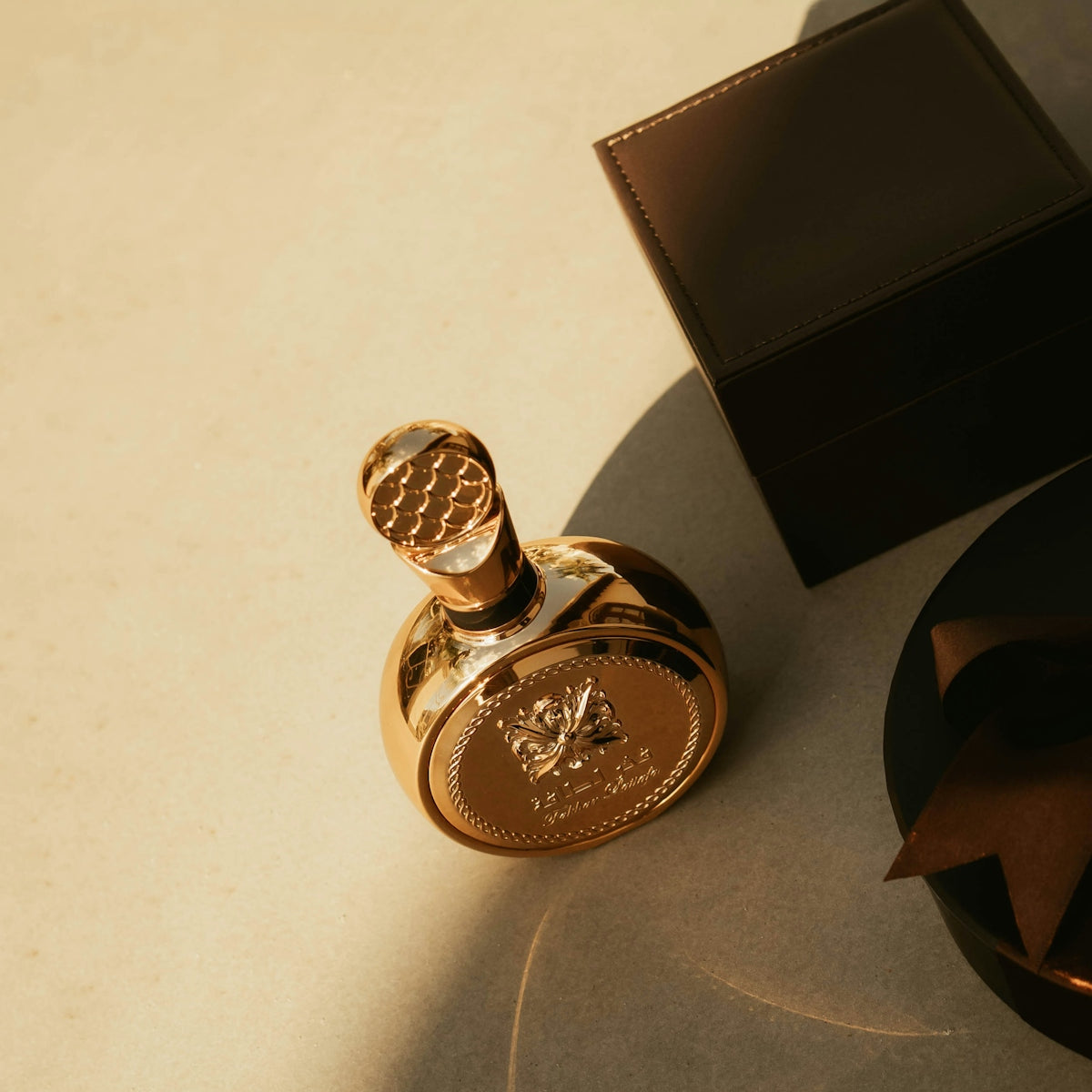 A gold perfume bottle with a dark box