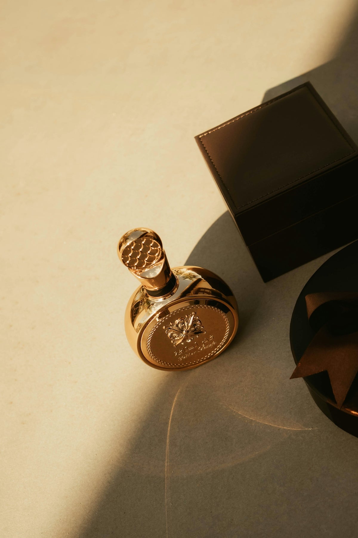 A gold perfume bottle with a dark box